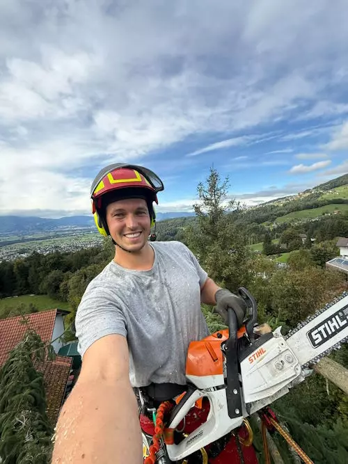 Michael Moosbrugger mit Helm und STIHL-Motorsäge bei der Baumpflege mit Blick über das Leiblachtal